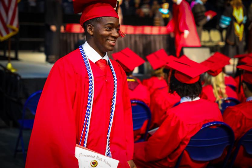 Students in red robes graduate